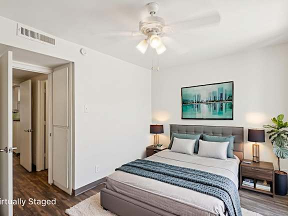 A bedroom with a bed, nightstands, and a painting on the wall.
