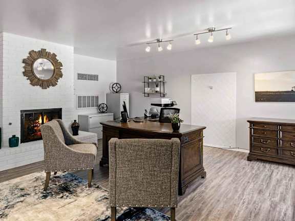 A room with a fireplace, a desk, and chairs.