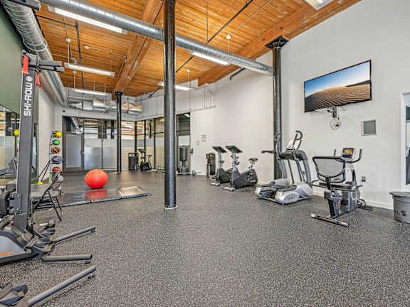 A gym with a variety of equipment including treadmills, exercise bikes, and weights at Riverwalk Apartments, Lawrence, Massachusetts 01843
