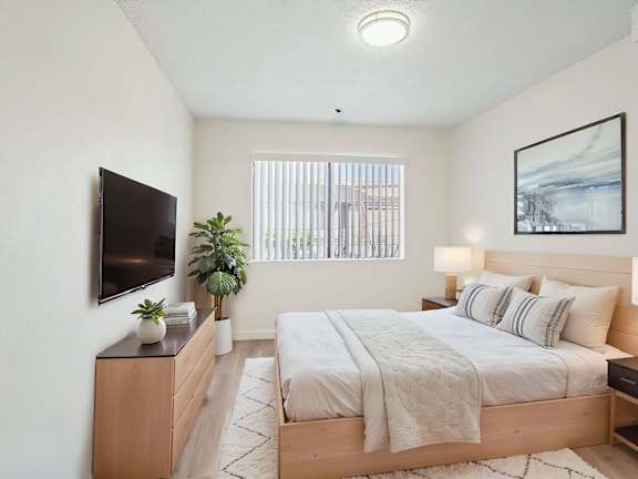 A bedroom with a large bed and a flat screen TV mounted on the wall.