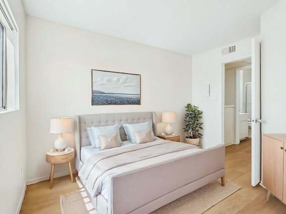 A bedroom with a large bed and a painting on the wall.
