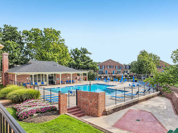 A pool area with a pavilion and a brick wall.