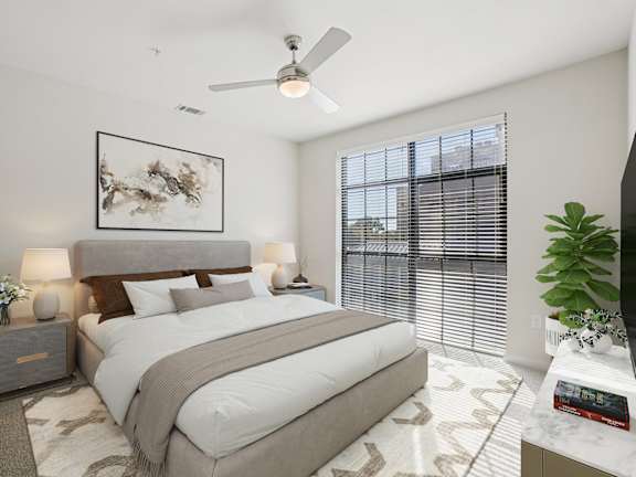 A bedroom with a large bed, a ceiling fan, and a painting on the wall.