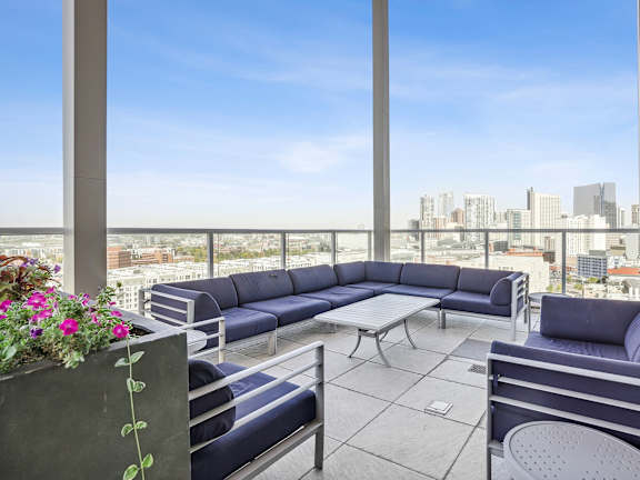 a patio with blue couches and a view of the city