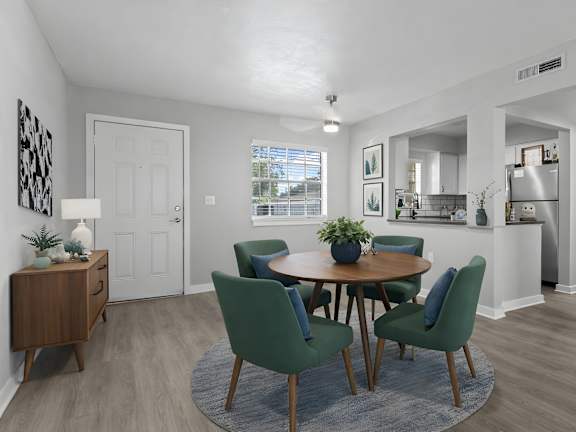 Watermarc Apartments dining area and kitchen with wooden table and green chairs.