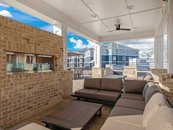 A patio with a couch, table, and a brick wall.