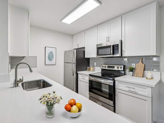 A modern kitchen with white cabinets and appliances.