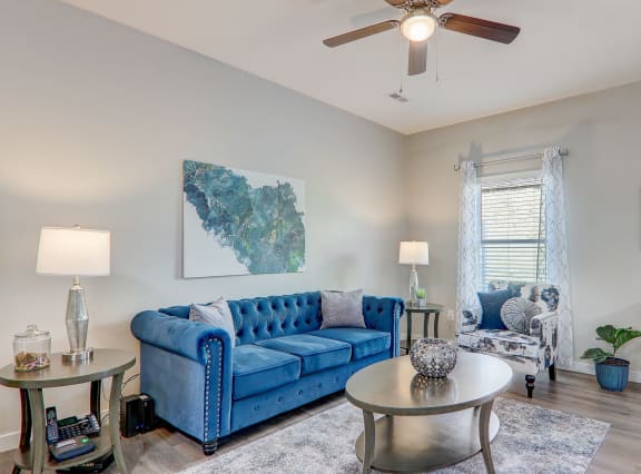 a living room with a blue couch and a ceiling fan