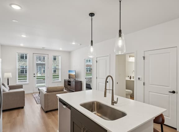 A modern kitchen with a white countertop and a stainless steel sink.