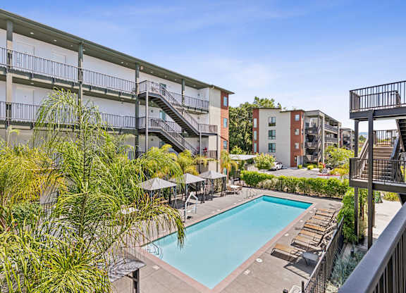 A pool surrounded by a balcony and trees.