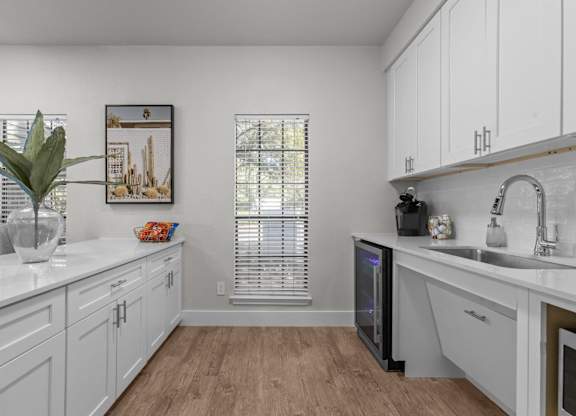 A kitchen with white cabinets and a wooden floor.