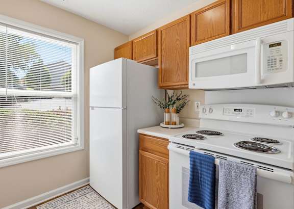 A kitchen with wooden cabinets and white appliances.