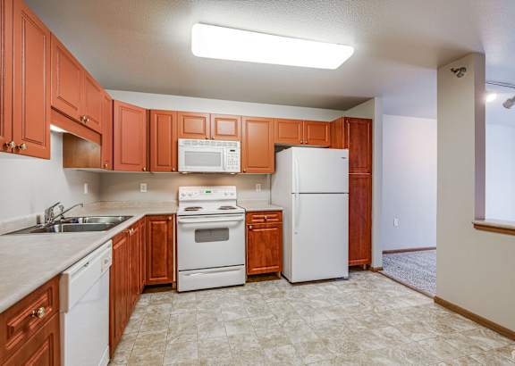 A kitchen with white appliances and wooden cabinets.