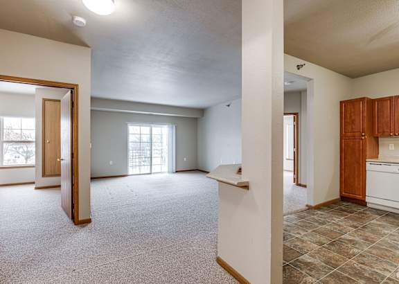 A large, empty room with a kitchen area to the right.