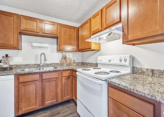 A kitchen with a white stove and wooden cabinets.