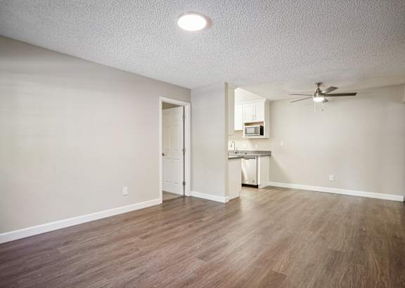an empty living room and kitchen with a ceiling fan