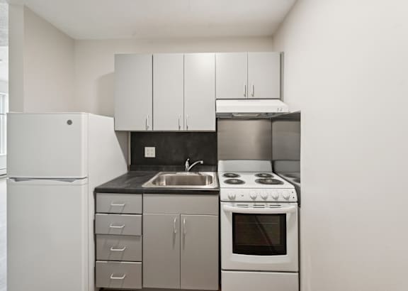 A white refrigerator is in a kitchen with a stove and sink.