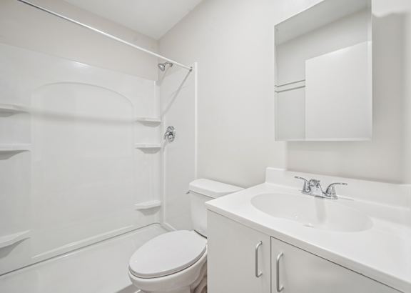 A white bathroom with a toilet, sink, and shower.