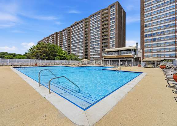 A pool area with chairs and a building in the background.