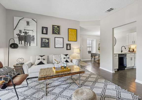 A living room with a white couch, a coffee table, and a rug with a geometric pattern.