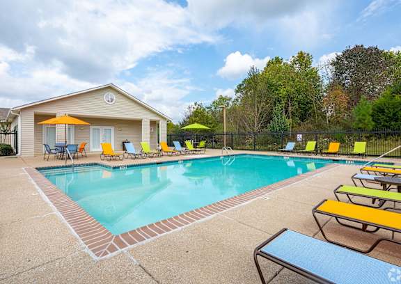 A pool area with a house and chairs.