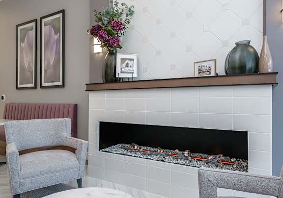 A fireplace with a white tile surround and a fire burning inside.