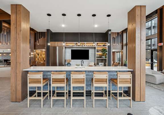 A modern kitchen with a bar area and wooden chairs.