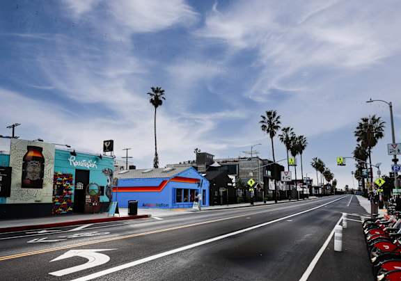 A street with a blue building on the left and palm trees on the right.