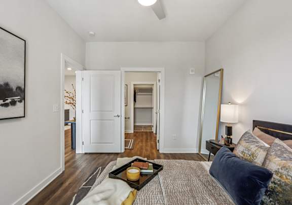 A bedroom with a bed, a couch, a coffee table, and a painting on the wall.