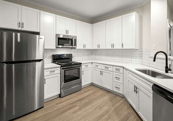 A kitchen with white cabinets and a stainless steel refrigerator.