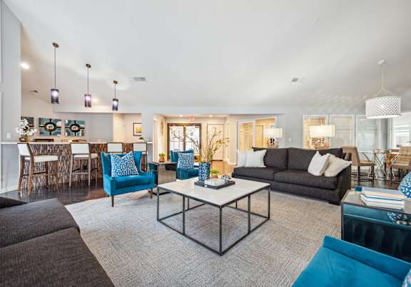 A modern living room with a black couch, blue chairs, and a white coffee table.
