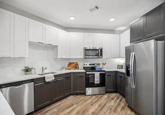 A modern kitchen with dark wood cabinets and stainless steel appliances.