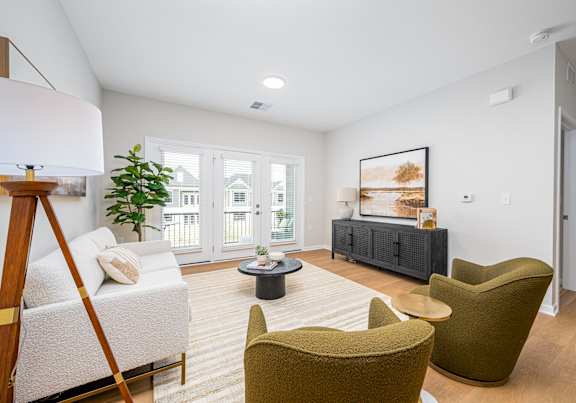 A living room with a white sofa, a green armchair, and a coffee table.