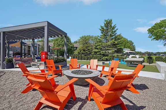 A black fence surrounds a green lawn with a white and orange seating area.