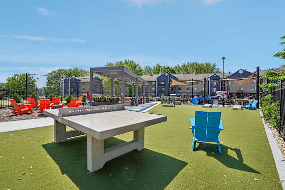 A black fence surrounds a green lawn with a white and orange seating area.