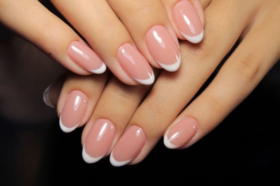 a close up of a hand with pink and white manicured nails