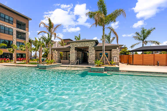 A pool in front of a house with a palm tree.