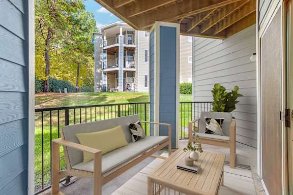 A balcony with a couch, chair, and table with a plant on it.