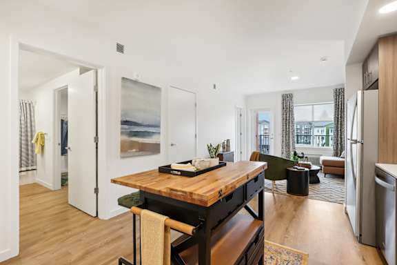 a living room with a wooden table and a kitchen