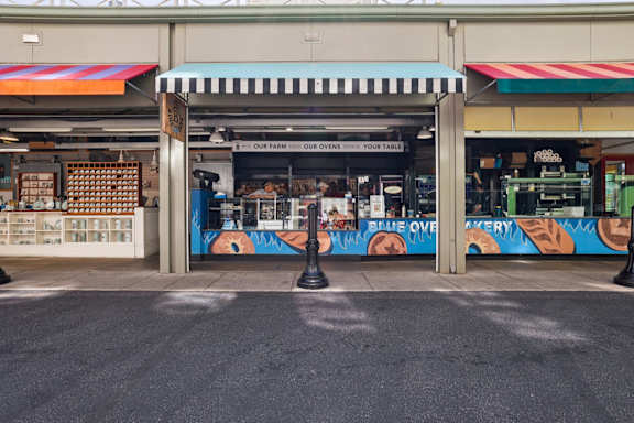 A street view of a storefront with a blue and white awning.