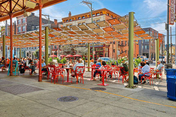 A group of people are sitting at tables under a canopy.