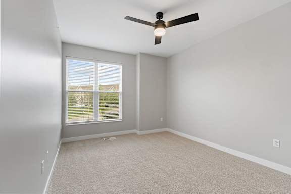A room with a ceiling fan and carpeted floor.