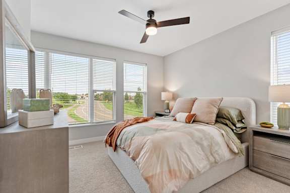 A bedroom with a bed, nightstand, and window with blinds.