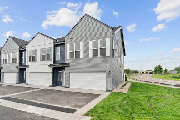 A modern house with a grey exterior and a large driveway.