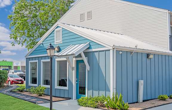 A blue house with a white roof and a red car parked in front.