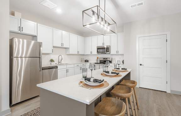 A modern kitchen with a large island and wooden chairs.