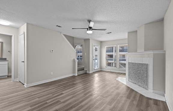an empty living room with a fireplace and a ceiling fan