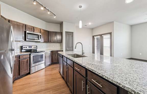 A kitchen with a granite countertop and stainless steel appliances.at North Creek, Hutto, TX, 78634