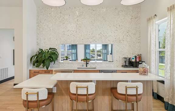 A kitchen with a white counter and brown chairs.
