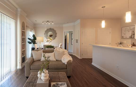 Open living area in the Islander apartment, with comfortable seating, a kitchen breakfast bar, pendant lights, and sliding glass doors.